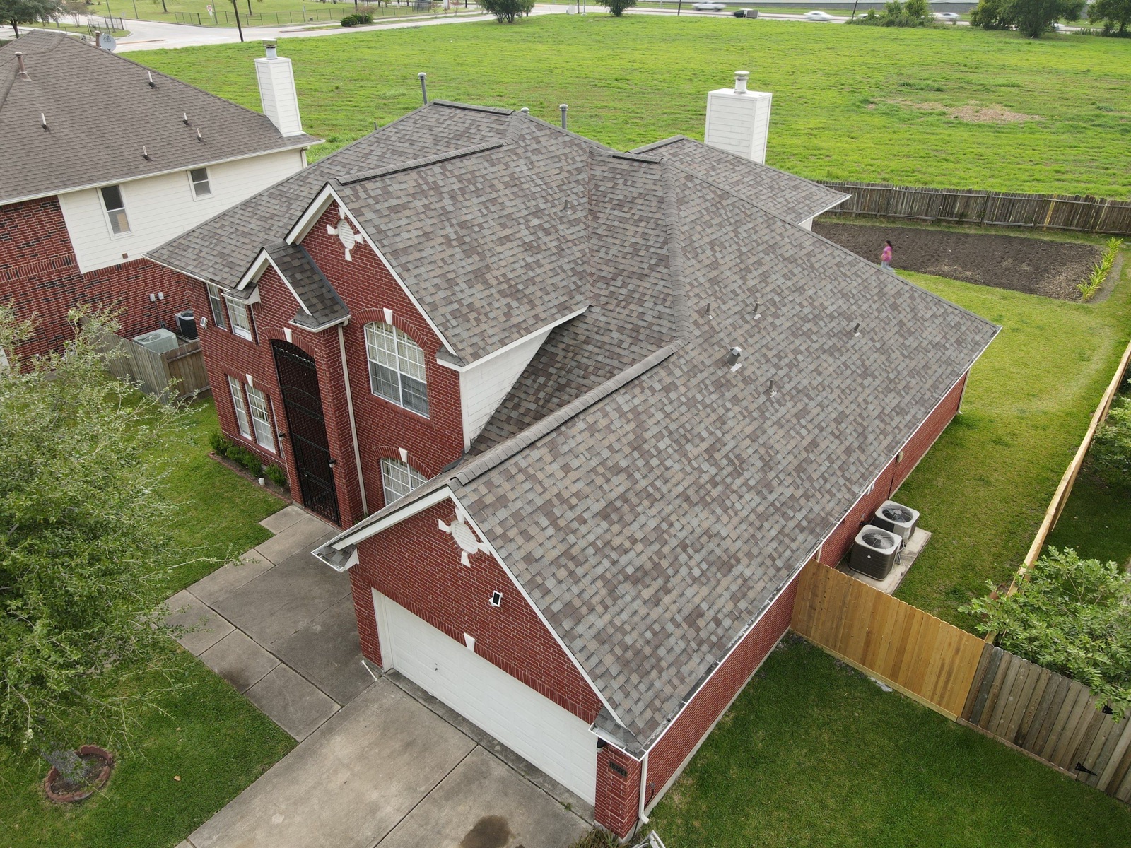 Completed architectural-shingle roof on a two-story Houston-area home, aerial view